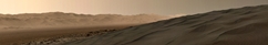 vignette-lien vers une vue de comment, au-del d'une dune de grande taille, dans le Bagnold Dune Field du cratre Gusev (qui longe le flanc nord-ouest du Mont Sharp), une vue se dgage sur un terrain plus gal et le mur du cratre se voit en arrire-plan